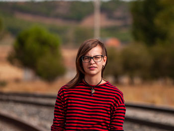 Portrait of smiling girl standing on railroad track