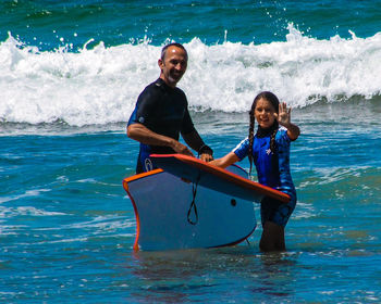 Portrait of father and daughter with surfboards in sea