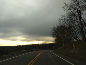 Road by trees against sky