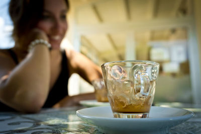 Woman drinking glass on table at restaurant