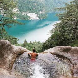 Rear view of man on rock by river