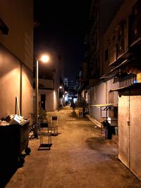 Empty footpath amidst illuminated buildings in city at night