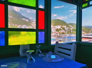 Chairs and table by window against sky