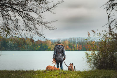 Woman with dog on lake against sky