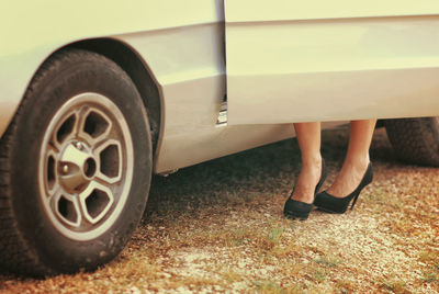 Low section of woman standing by car