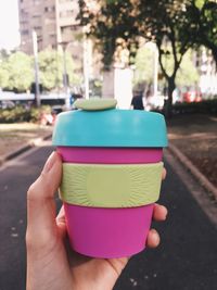 Cropped hand of woman holding cup on street