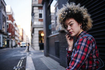 Portrait of young woman standing on street in city