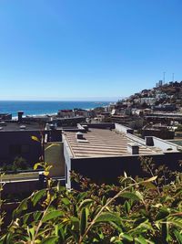 View of townscape by sea against clear blue sky