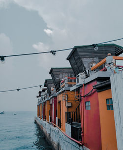 Houses by sea against sky in city