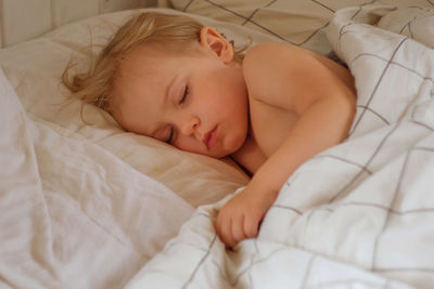 Close-up of cute baby boy sleeping on bed at home