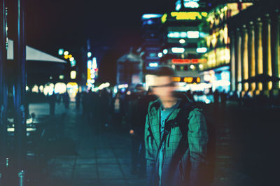 Man walking on illuminated street in city at night