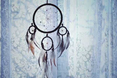 Close-up of dreamcatcher hanging against curtain