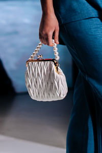 Fashionable details of a white clutch with beads in a woman's hand. elegant clothing and accessories