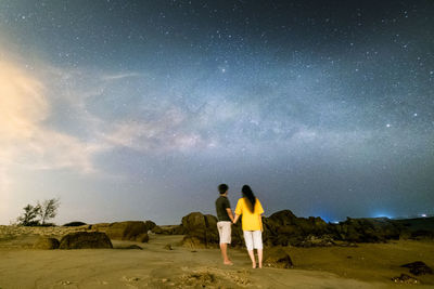 Men standing on field against sky at night