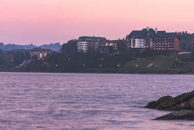 Scenic view of sea and buildings against sky at sunset