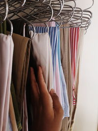 Cropped hand of person choosing clothes hanging on coathangers