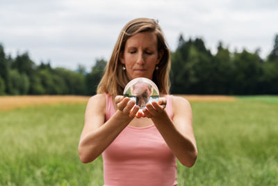 Young woman holding bubbles while standing on field