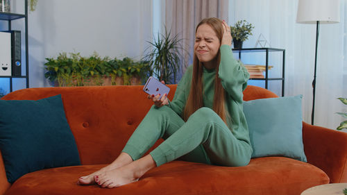 Portrait of young woman sitting on sofa at home