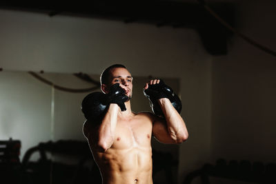 Shirtless male athlete training in gym