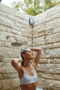 Portrait of young woman standing against wall