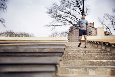 Low angle view of male athlete running on steps at stadium