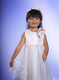 Portrait of a smiling girl standing against blue sky