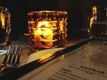 Close-up of illuminated candles on glass table