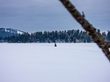 Man skiing on snow covered field against sky