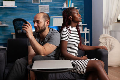 Young woman with man sitting on sofa at home