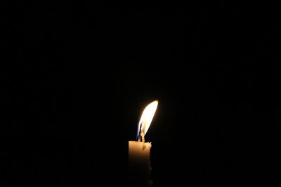 Close-up of lit candle against black background