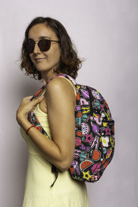 Portrait of woman wearing sunglasses standing against wall