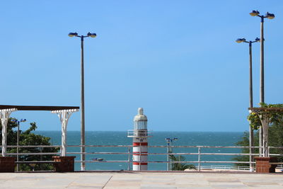 Street light and lighthouse against sea and clear sky on sunny day