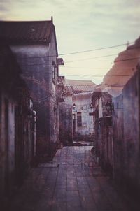 Footpath amidst houses in town against sky