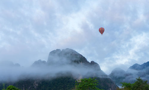 Hot air balloons flying over mountain against sky