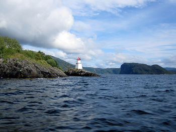 Lighthouse by sea against sky