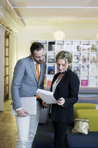 Mature businesswoman with male colleague reading documents in creative office