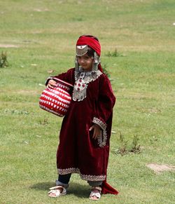 Portrait of girl holding container while standing on grass