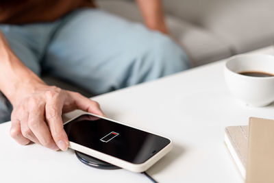 Midsection of woman using mobile phone at table