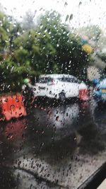 Cars seen through wet glass window in rainy season