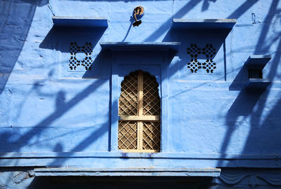 Low angle view of windows amidst blue wall