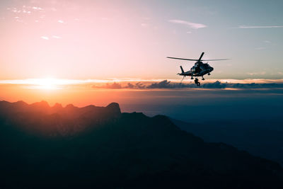 Silhouette of helicopter flying in sky