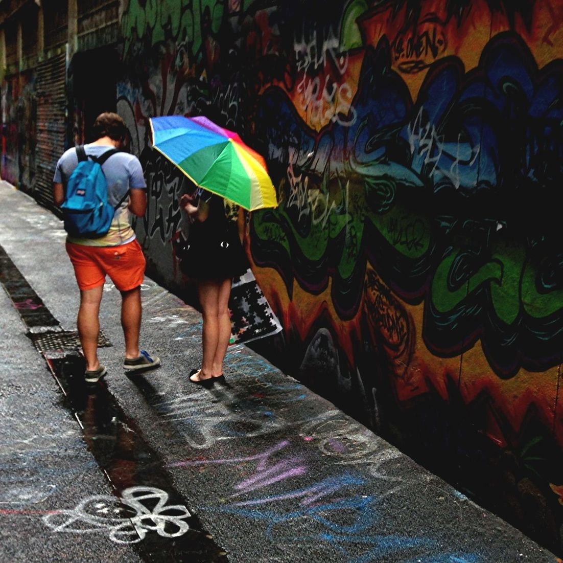 full length, graffiti, lifestyles, standing, domestic animals, walking, casual clothing, animal themes, leisure activity, street, mammal, men, one animal, pets, rear view, outdoors, day, built structure