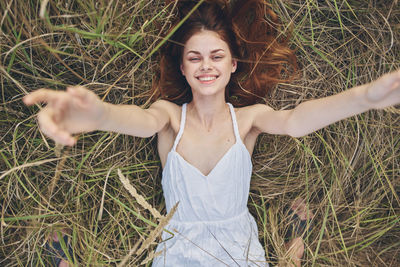 Portrait of smiling young woman lying on field