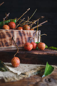 Close of lychees by container on wooden table