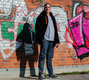 Fashionable mature man standing against graffiti wall