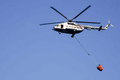 Low angle view of helicopter flying against clear blue sky