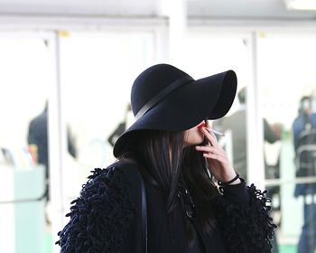 Woman wearing black hat smoking cigarette
