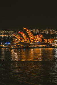 Illuminated bridge over river in city at night