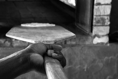 Close-up of man holding wooden paddle by oven