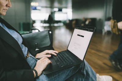 Female freelancer working on laptop while sitting at airport terminal